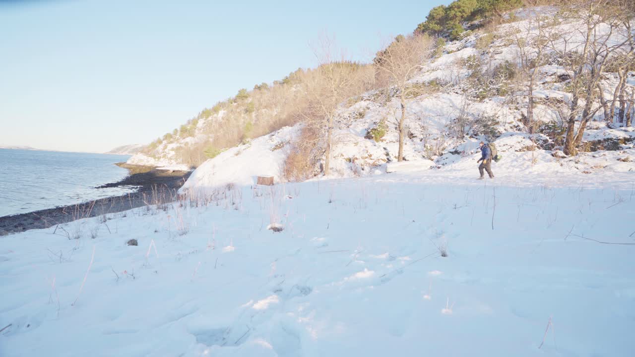 호숫가 옆 눈 덮인 산에서 애완견과 배낭 여행을 하는 먼 남자