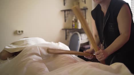 woman receiving a back massage with a wooden stick