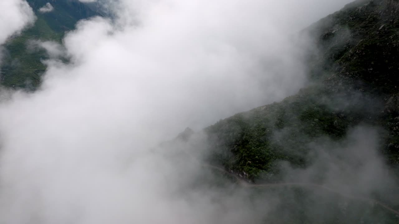 Drone shot at sunrise, moving through the clouds to reveal the breathtaking Colca Canyon, with soft morning light illuminating the dramatic landscape.