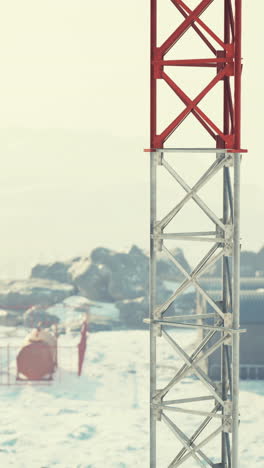 primer plano de una torre roja y metálica en un paisaje nevado