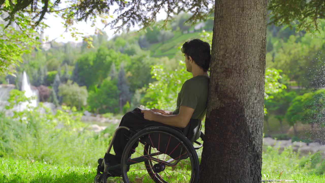 Disabled teenager sitting in a wheelchair reading a book.