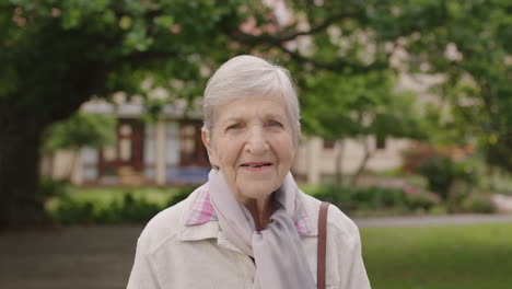 portrait of senior elderly caucasian woman smiling happy at camera enjoying sunny day in park