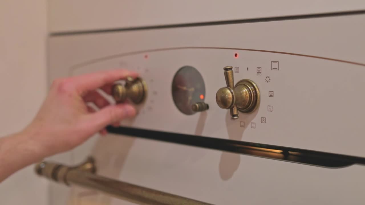 Primo piano di mani che regolano le manopole di un forno professionale bianco durante la preparazione di focaccia fatta in casa. Controllo di temperatura e modello su forno elettrico