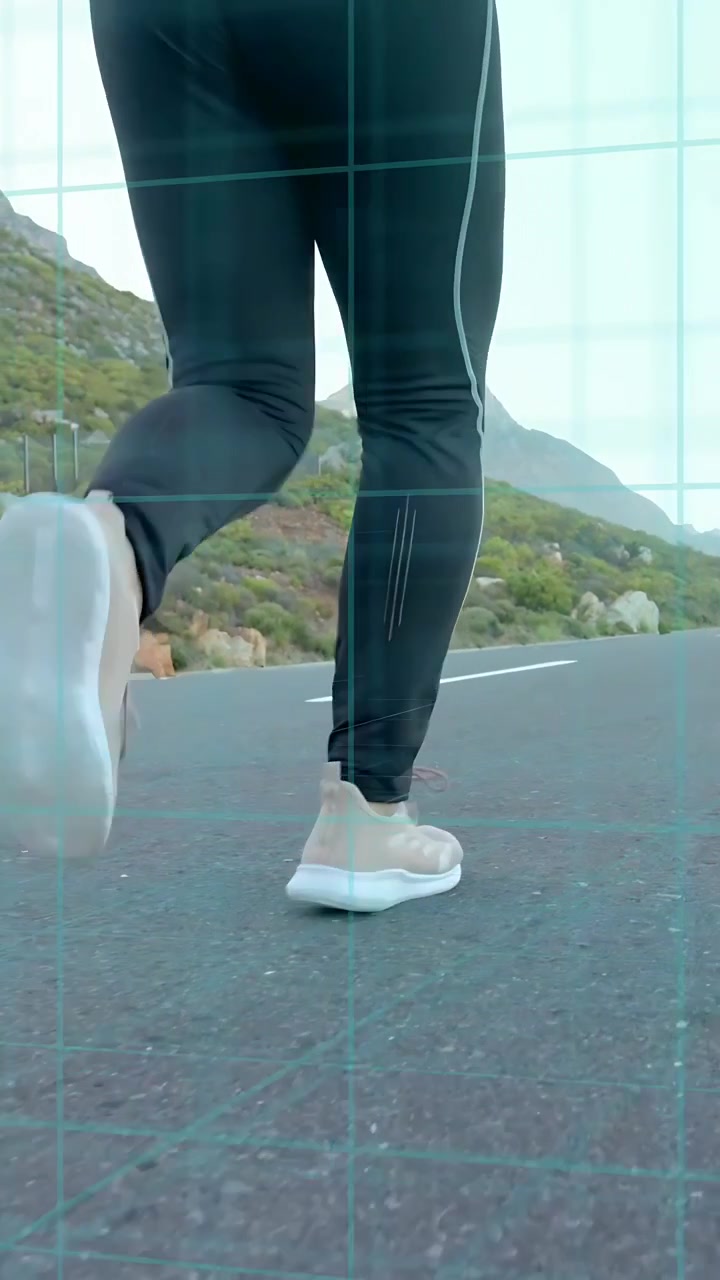 Dikey video: Dağ yolunda koşan kadın, topuğun yukarı kalktığını gösteren alçak açılı kamera ve bacaklarda fitness ızgarası.