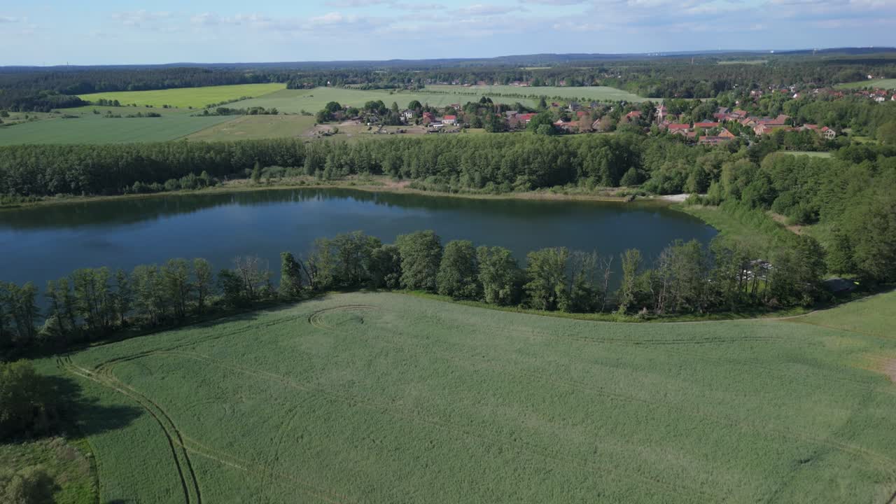 Aerial view of a green field and lake during a sunny summer day