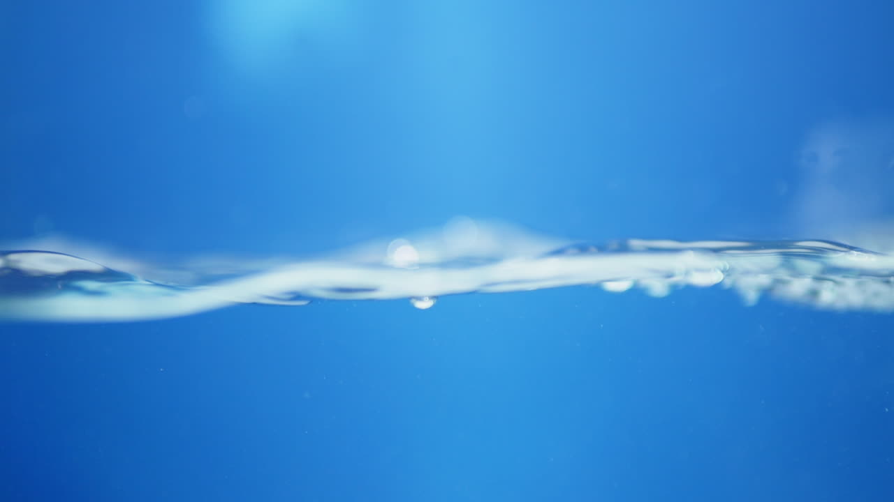 Macro shot of water droplets creating intricate patterns, reflecting light for a shiny and creative look at the beauty of liquid motion