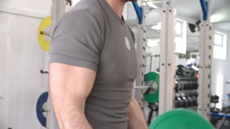 joven entrenando con pesas con barras en un gimnasio