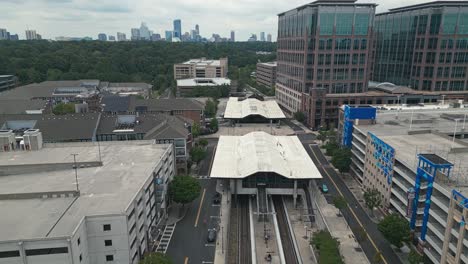 Sobrevuelo-Aéreo-De-La-Estación-Lindbergh-Marta-Y-árboles-Del-Parque-Con-El-Horizonte-De-Buckhead-Atlanta-En-El-Fondo,-Estados-Unidos