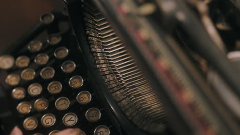 slow tilt up from woman's hands typing on vintage typewriter keys to stickers hitting paper