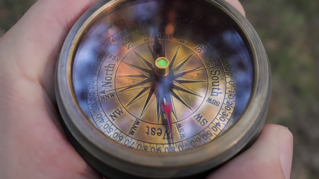 la mano del viajero sostiene una vieja brújula direccional en el bosque de verano. la persona usa la brújula para encontrar la ubicación. concepto de viaje de primer plano.