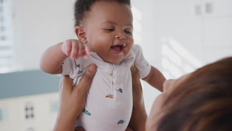 Proud-Grandmother-Cuddling-And-Playing-With-Baby-Grandson-In-Nursery-At-Home