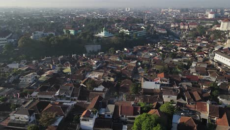 Aerial-view-of-downtown-Yogyakarta,-visible-mosque-between-buildings,-houses-and-river-in-the-morning