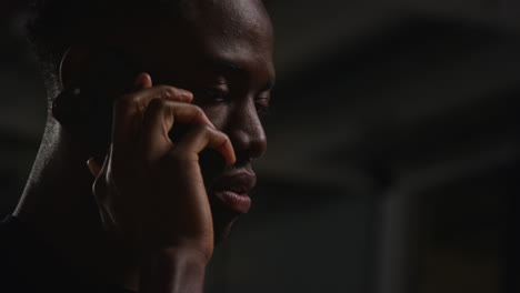 close up of unhappy and depressed young man sitting on sofa at home making call on mobile phone at night 2