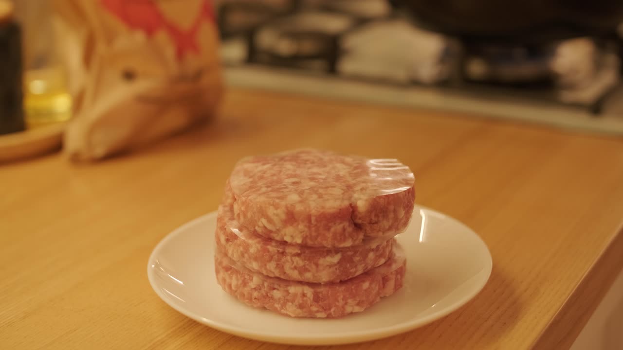Raw meat patties frying in pan on kitchen stove