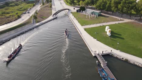 Canoeing-in-water-canal-near-city-of-Aveiro,-aerial-orbit-view