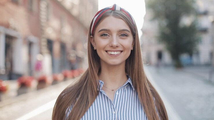 Ragazza felice che saluta con la mano e sorride alla fotocamera.