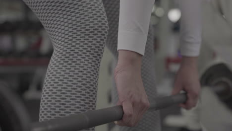 cerca de piernas y manos femeninas atléticas sexy levantando pesas en el gimnasio