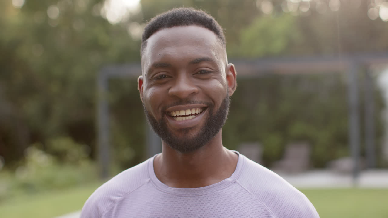 Portrait of happy african american man smilling in garden,, in slow motion