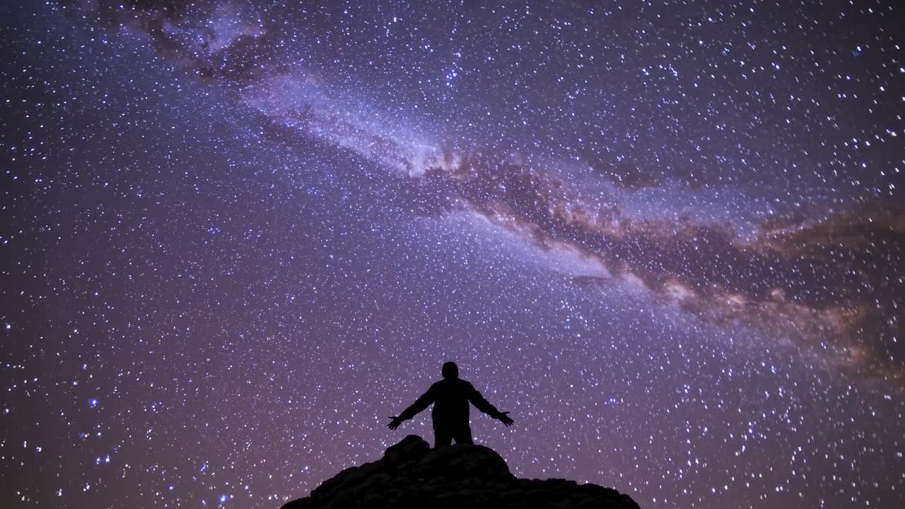 Silhouette of a person under a starry sky, captured from a low angle