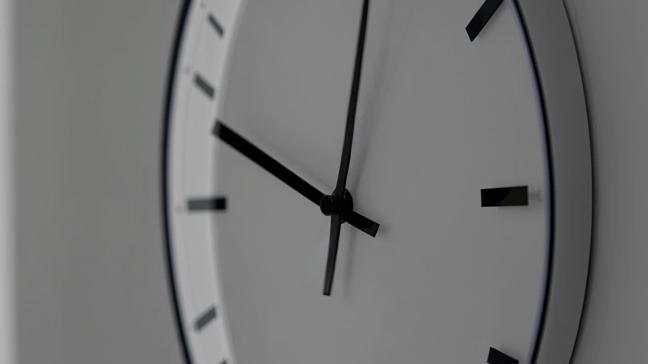 Primo piano di un orologio da parete moderno dal design minimalista. L'orologio presenta un quadrante bianco e lancette nere