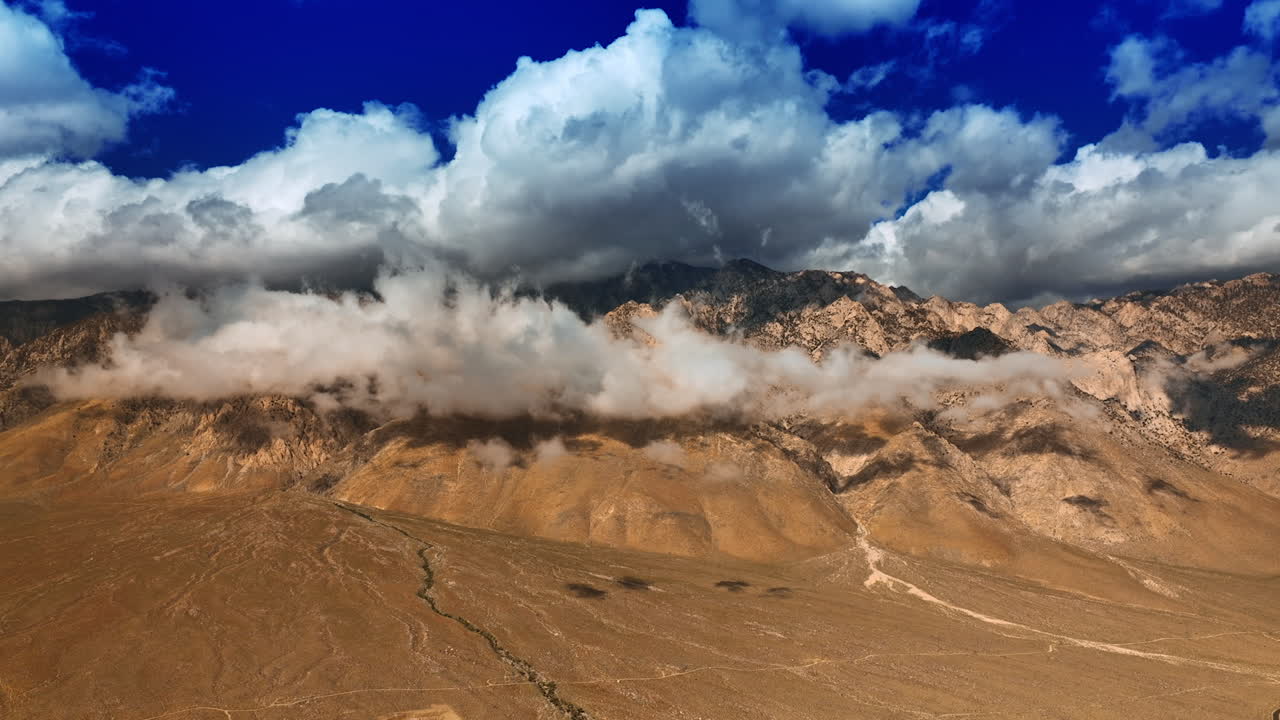 Soft white cloudscape coating the tops of mountains. View on Death Valley from aerial perspective.