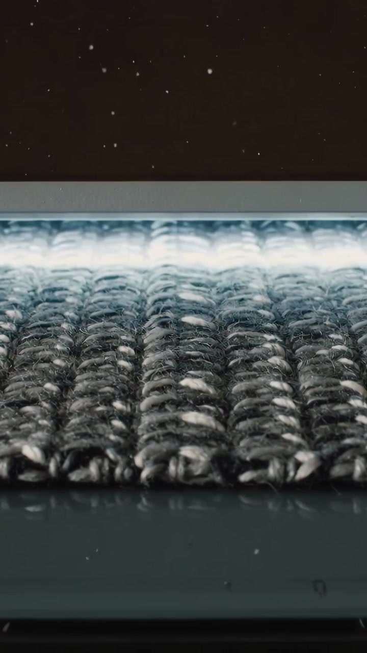 Vertical video: Shifting camera revealing gray woven fabric on gloss base exposing fibers under LED