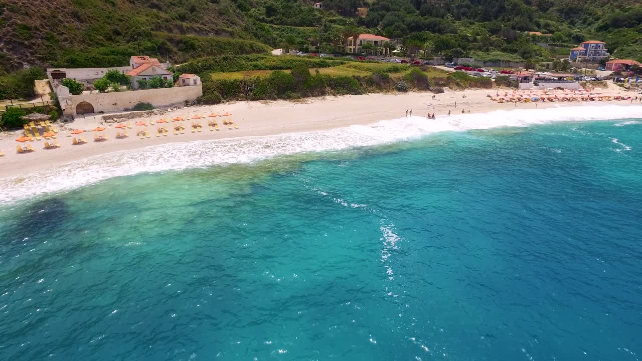 Drone panning in front of the Petanoi Beach shoreline while showing the white, sandy shoreline facing the Mediterranean Sea in Greece