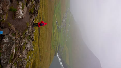 mujer descendiendo de la montaña villingardalsfjall regresando a la aldea de vidareidi