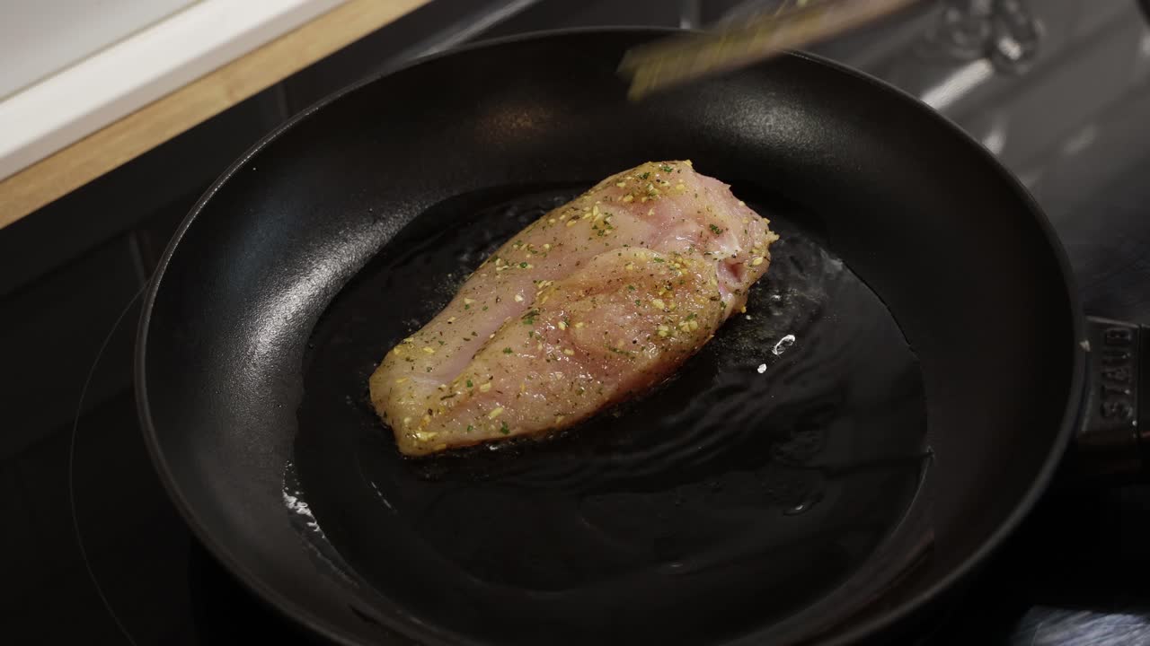 Aggiungere olio in una padella calda dopo aver posizionato petti di pollo speziati per la frittura