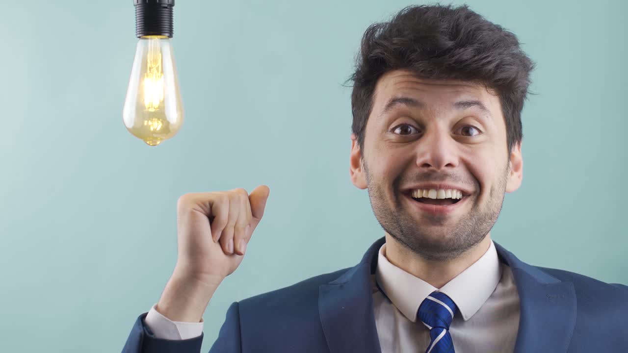 un hombre de negocios inteligente tiene una idea y enciende la lámpara chasqueando los dedos. eureka.