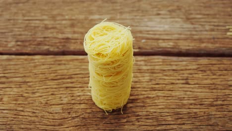 One-roll-of-spaghetti-on-wooden-table-background