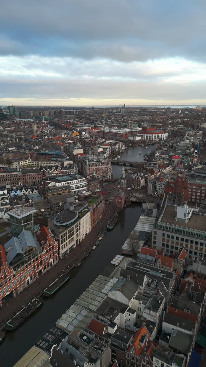 Vertical drone shot rotating over a canal in downtown Amsterdam, sunset in Holland