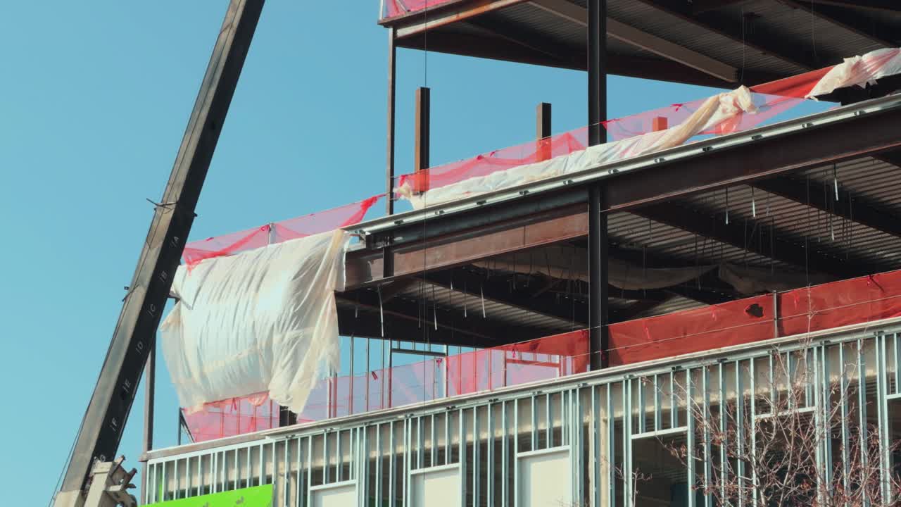 Inquadratura fissa di vento leggero che muove delicatamente i teli di plastica su un edificio moderno in costruzione.