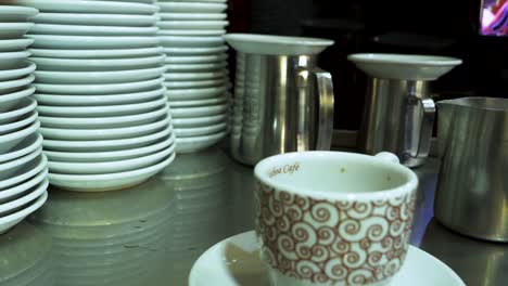 Barista-adding-milk-to-coffee-in-busy-cafe---close-up