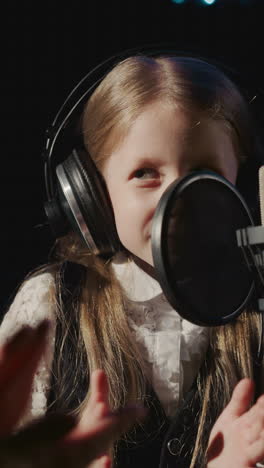 man claps hands with girl in audio studio. little girl happy finishing vocal lesson with professional mentor. end of hard training day at music school