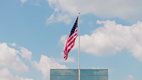 Waving-American-Flag-on-flagpole-against-blue-sky-and-clouds