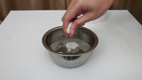 woman's hand squeeing of wet cotton in the bowl