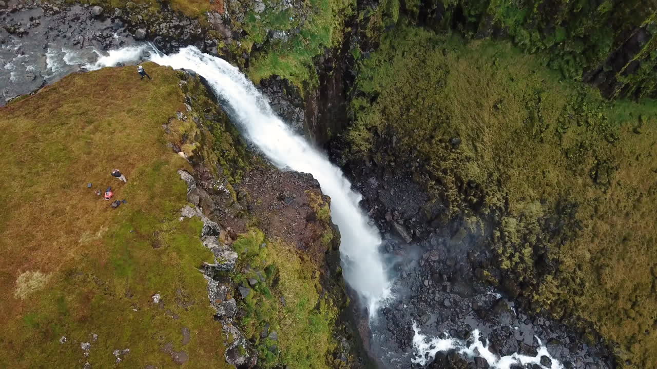 Stunning 4k aerial of a large waterfall flowing down moss covered mountain