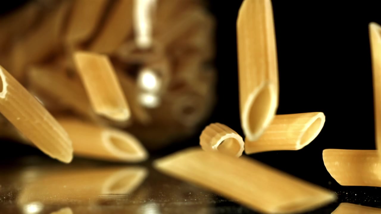 Penne che cadono al rallentatore su sfondo nero