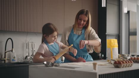 homemade bread, woman and her little daughter are kneading dough in home kitchen