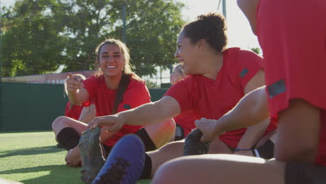 female soccer team warming up with stretches in training against flaring sun