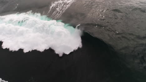 slow motion wave folds in half with glowing crest under soft evening sky