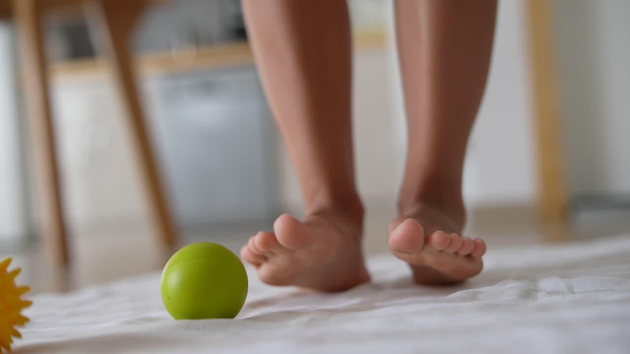 초록색 공을 가진  천에 아이의 벌거벗은 발