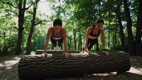 two women exercising on a log in the forest