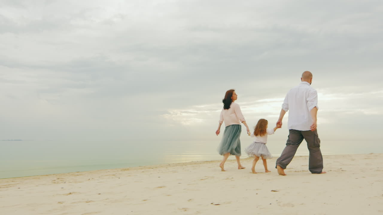 잔잔한 바다의 해안을 따라 함께 걷는 행복한 가족