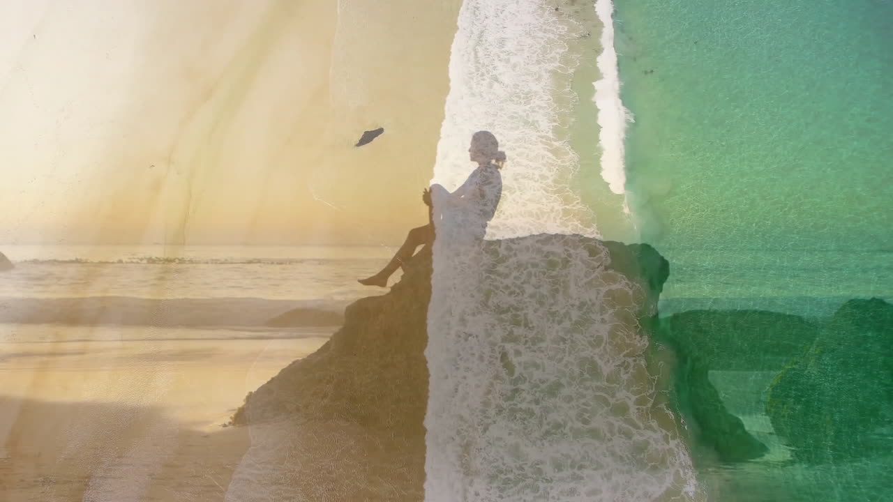 Ocean waves and colorful textures overlaying silhouette of person on rock animation