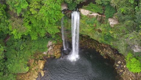 aerial: tall mexican misol-há waterfall cascading over canyon, arc shot