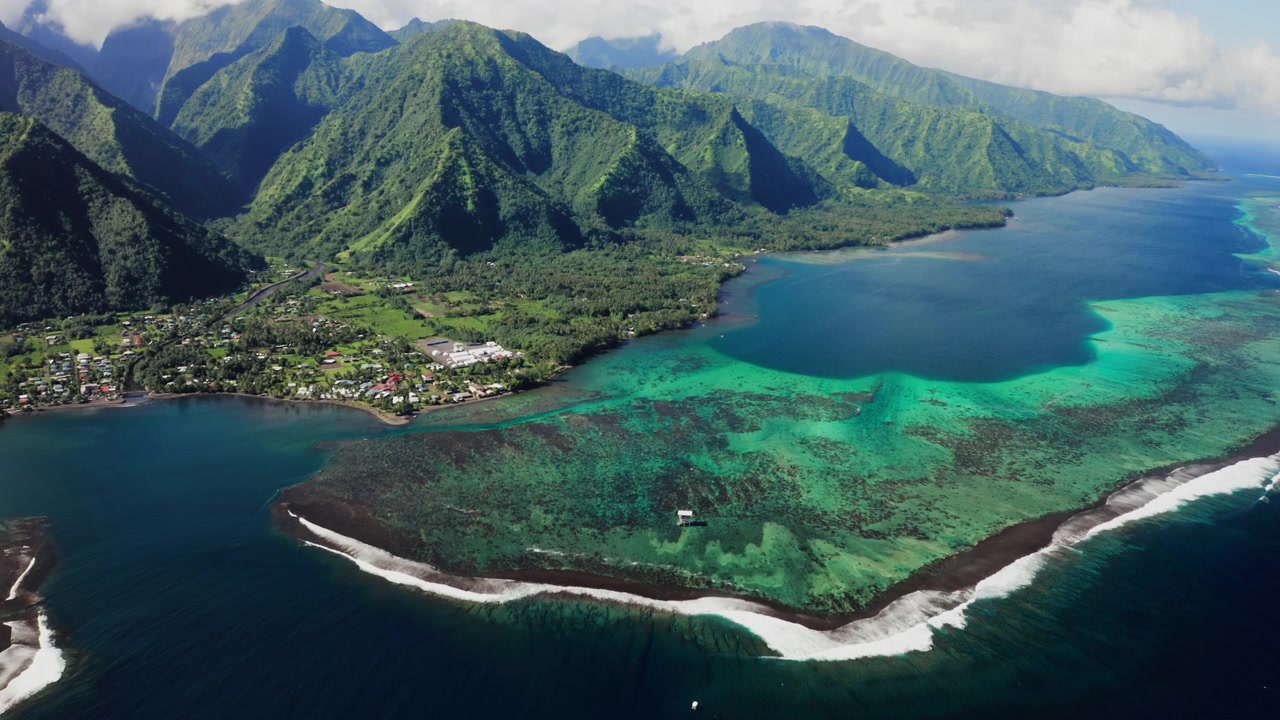 Drone paljastaa turkoosinsinisen aukon Teahupoon laguunissa, Tahitilla, laakson rinteiden laskeutuessa kohti alapuolella olevaa koralliriutan reunaa.