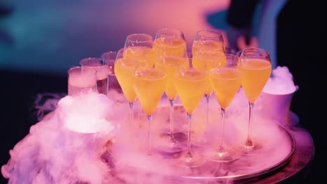 orange cocktails with dry ice in tall glasses surrounded by a smoky, atmospheric setting