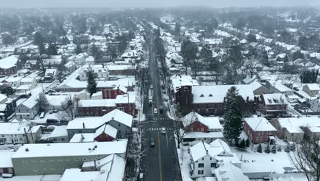 aerial pull back reveal over small town in america street during snow storm